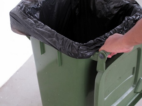 Worker wearing PPE handling waste at a skip site